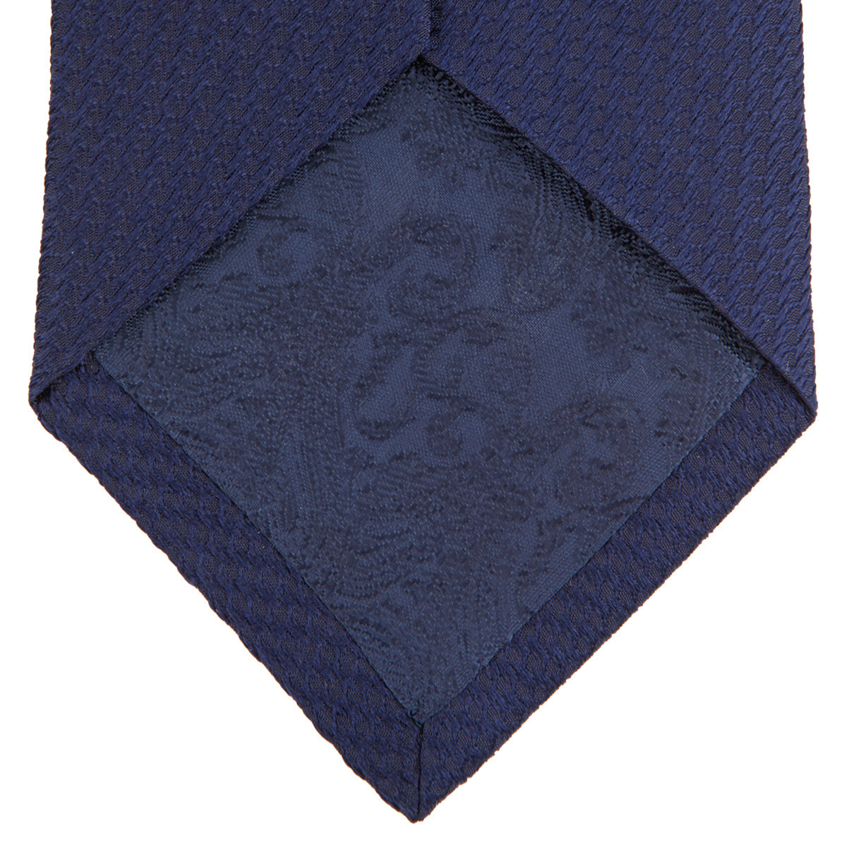 View 4 of product The Turnbull & Asser Navy Lace Silk Tie, featuring a subtle lace weave texture, is displayed rolled up on a plain white background.