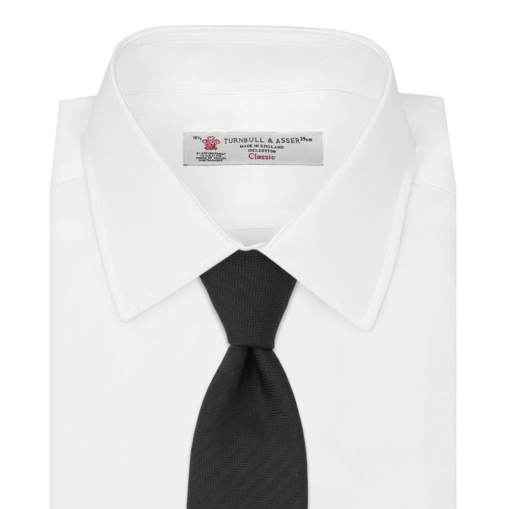 A Long Black Herringbone Silk Tie by Turnbull & Asser is shown rolled up on a plain white background.