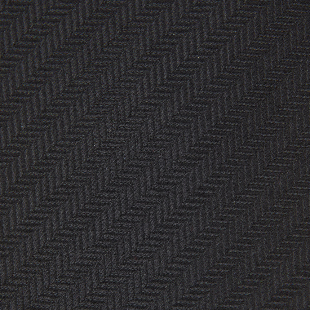 The Turnbull & Asser Black Herringbone Silk Tie is rolled up and displayed on a plain white background, showcasing its classic style and subtle chevron pattern.