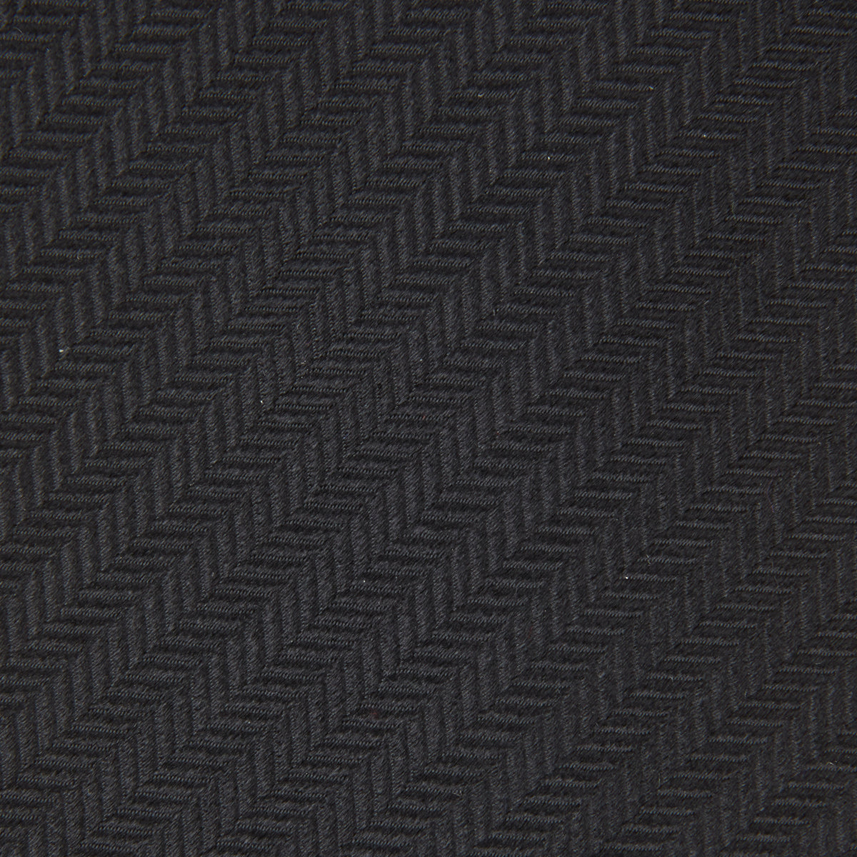 View 3 of product The Turnbull & Asser Black Herringbone Silk Tie is rolled up and displayed on a plain white background, showcasing its classic style and subtle chevron pattern.