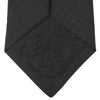 View 4 of product The Turnbull & Asser Seven-Fold Black Herringbone Silk Tie, featuring a subtle weave, is shown rolled up against a plain white background.