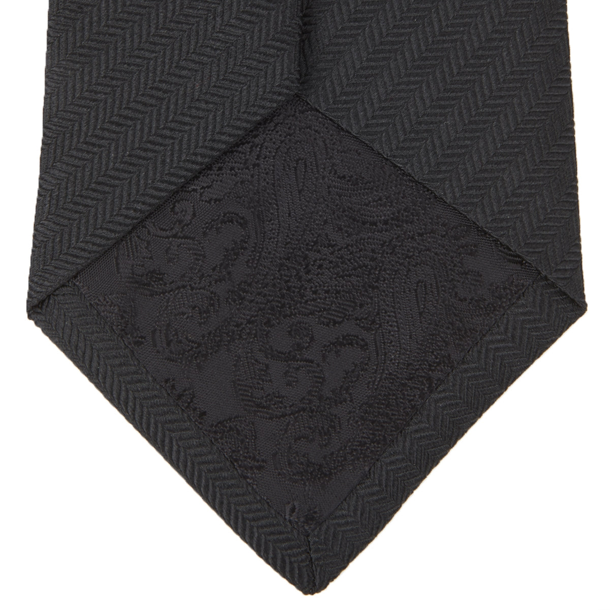 View 4 of product The Turnbull & Asser Seven-Fold Black Herringbone Silk Tie, featuring a subtle weave, is shown rolled up against a plain white background.