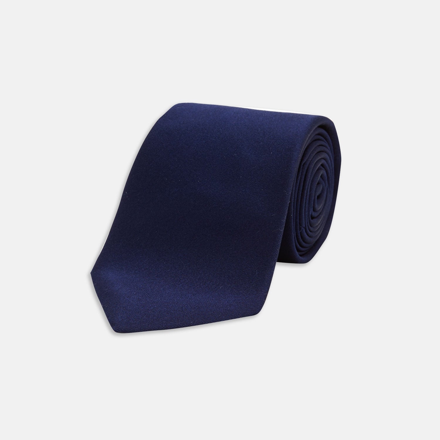View 1 of product The Turnbull & Asser Long Navy Plain Satin Silk Tie is neatly rolled and displayed against a plain white background.