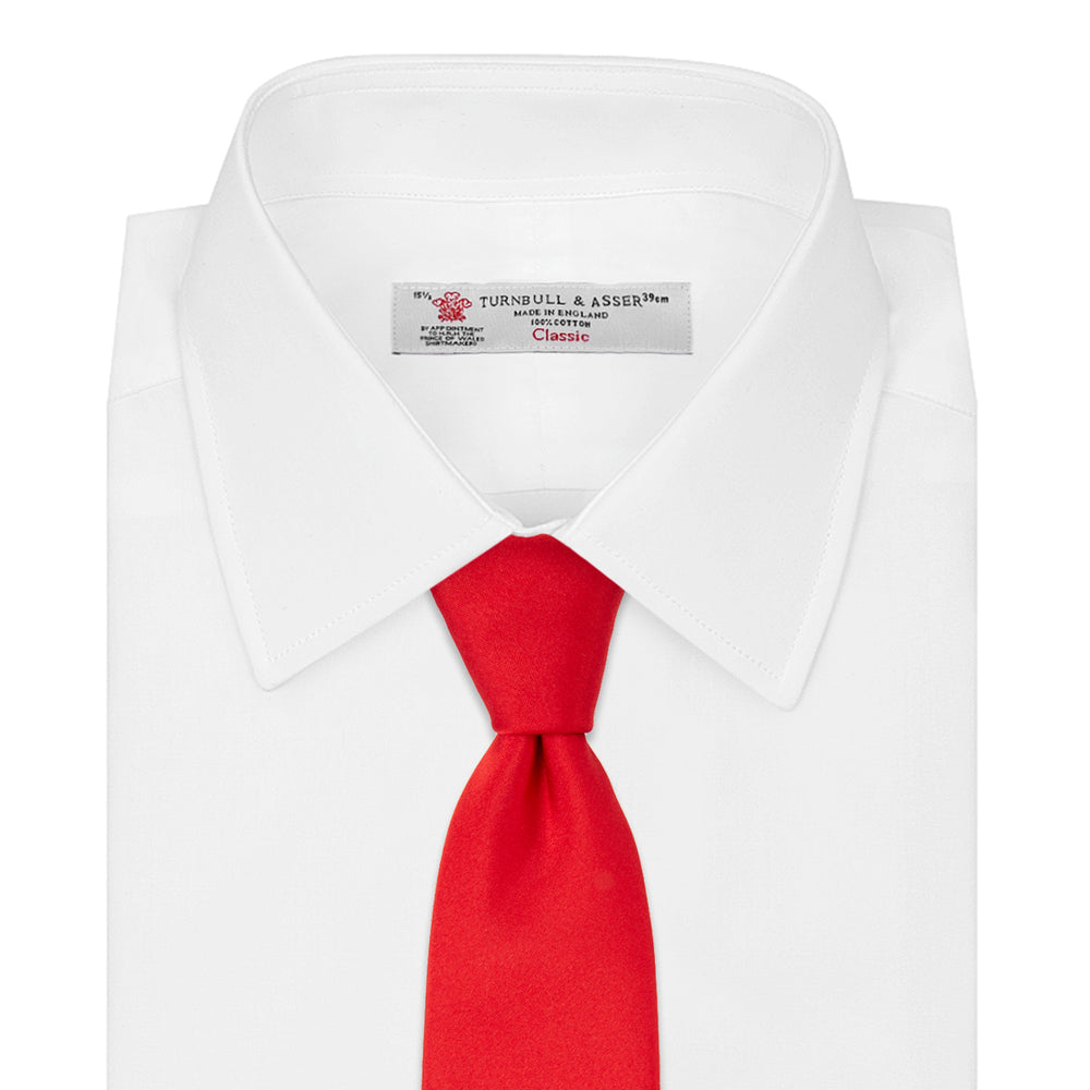 A Red Plain Satin Silk Tie by Turnbull & Asser is neatly rolled and displayed against a plain light gray background.
