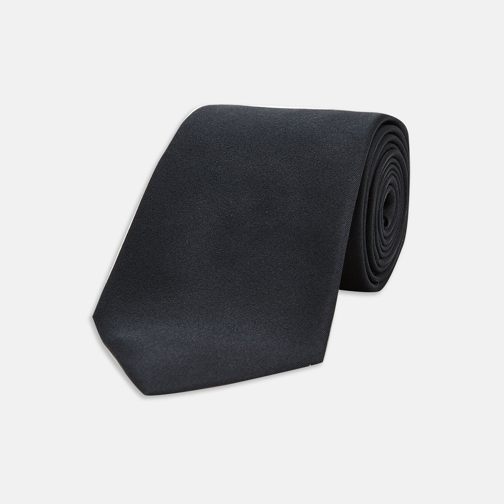 The Turnbull & Asser Slim Black Plain Satin Silk Tie is neatly rolled on a white background—an essential accessory for smart dress and formal occasions.