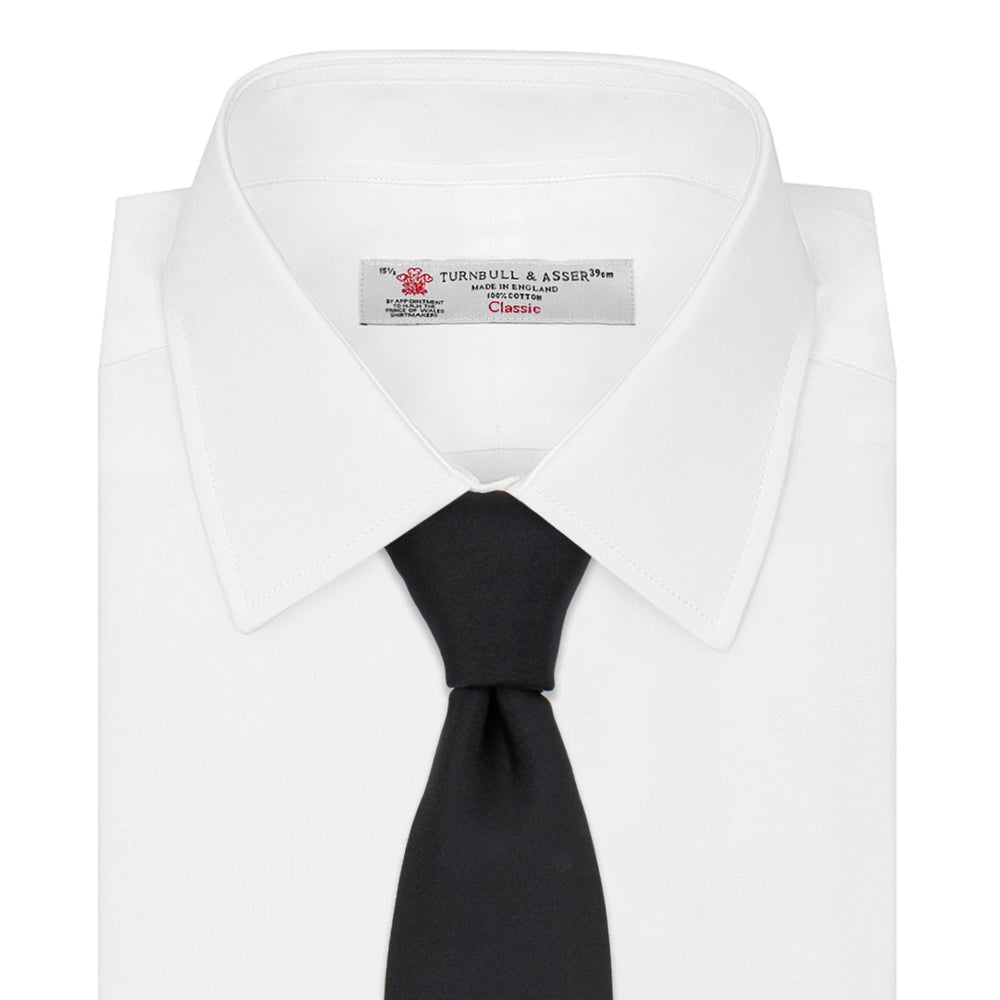 The Turnbull & Asser Black Plain Satin Silk Tie, neatly rolled and shown on a white background, adds versatile elegance to any formal outfit.