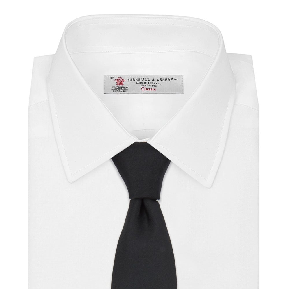 The Turnbull & Asser Slim Black Plain Satin Silk Tie is neatly rolled on a white background—an essential accessory for smart dress and formal occasions.