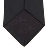 View 4 of product The Turnbull & Asser Black Plain Satin Silk Tie, neatly rolled and shown on a white background, adds versatile elegance to any formal outfit.