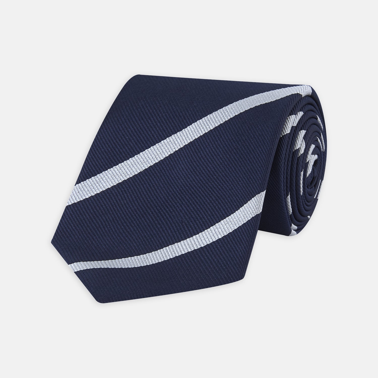 View 1 of product Turnbull & Asser’s Slim Navy and White Blazer Stripe Repp Silk Tie features two white diagonal stripes, rolled neatly on a white background—an ideal accessory to complement any office shirt.