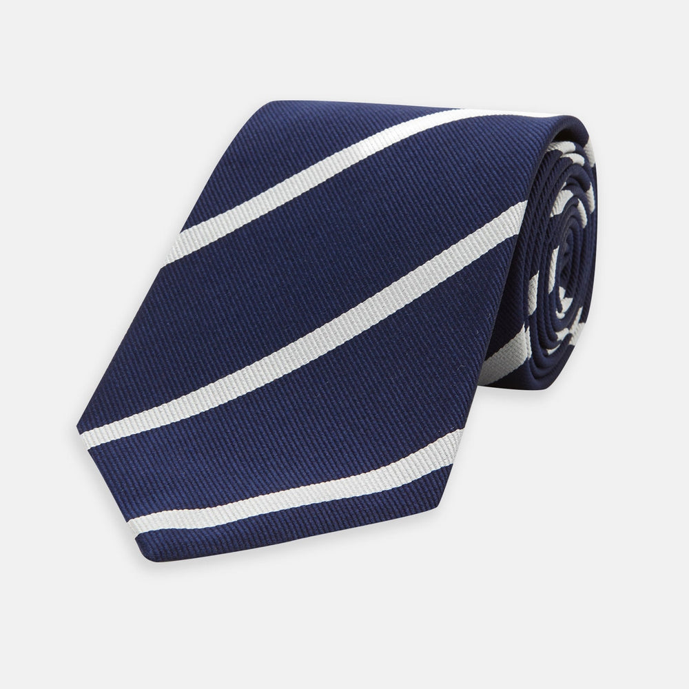 The Turnbull & Asser Long Navy and White Blazer Stripe Repp Silk Tie is shown rolled at one end, highlighting its diagonal stripes, against a plain white background.