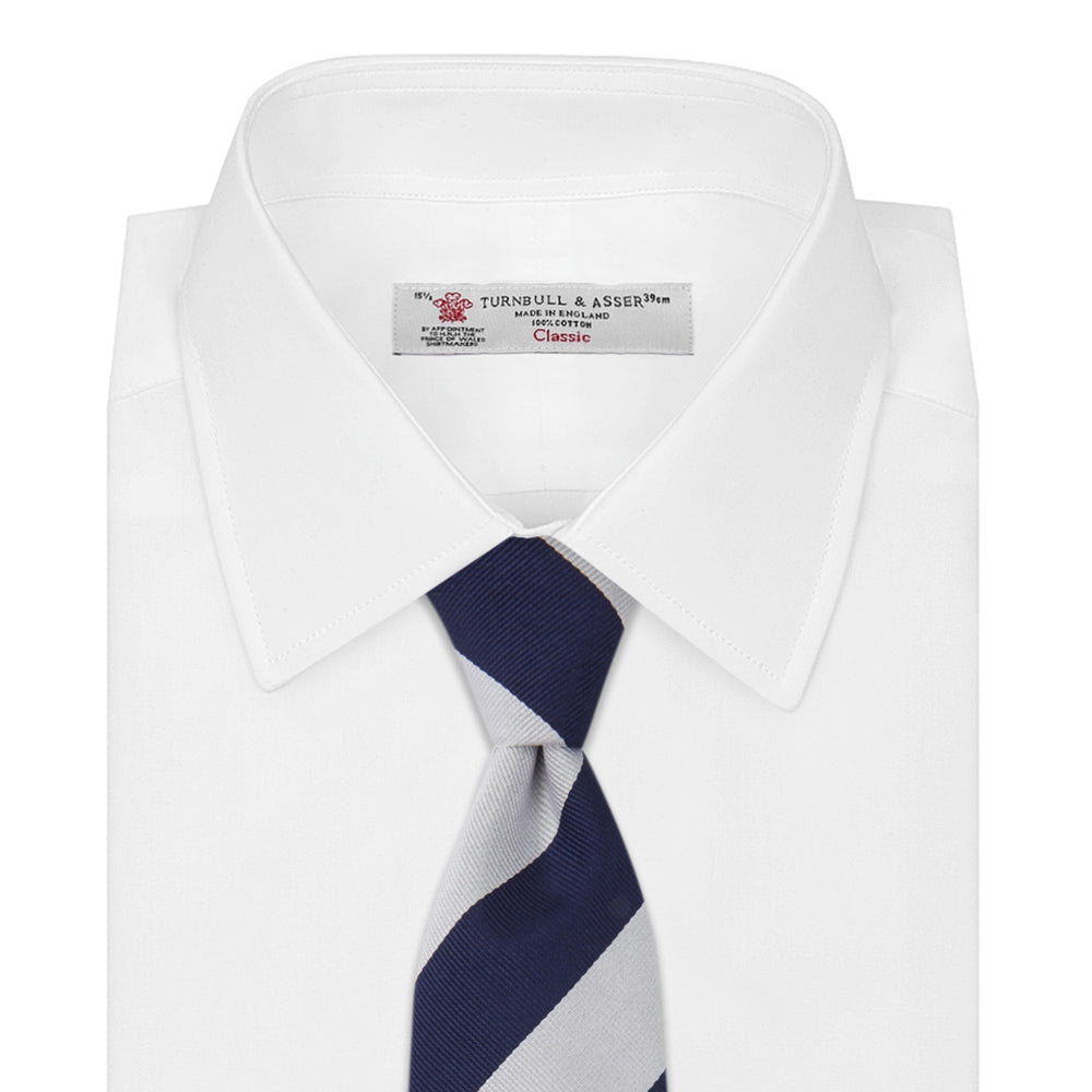 The Long Navy and Off-White Block Stripe Repp Silk Tie by Turnbull & Asser, featuring diagonal stripes, is rolled up and displayed on a plain white background—ideal for pairing with an office shirt.
