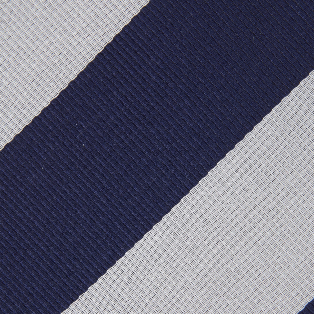 View 4 of product The Long Navy and Off-White Block Stripe Repp Silk Tie by Turnbull & Asser, featuring diagonal stripes, is rolled up and displayed on a plain white background—ideal for pairing with an office shirt.