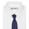 View 2 of product The Turnbull & Asser Seven-Fold Navy & White Spot Herringbone Silk Tie features a navy base with white polka dots and a classic herringbone weave, displayed rolled up on a plain white background.