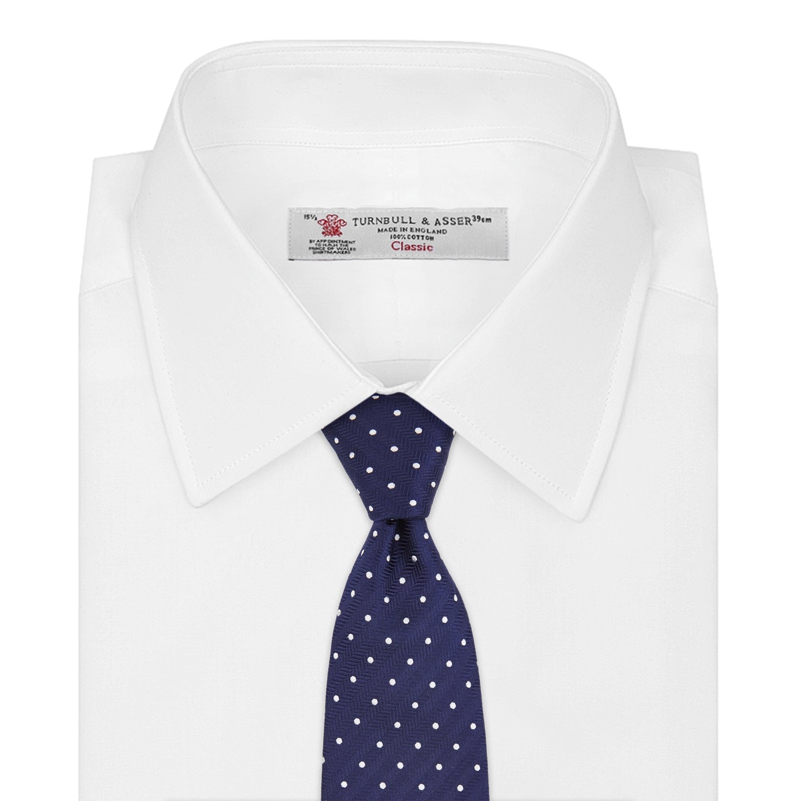 View 2 of product The Turnbull & Asser Seven-Fold Navy & White Spot Herringbone Silk Tie features a navy base with white polka dots and a classic herringbone weave, displayed rolled up on a plain white background.