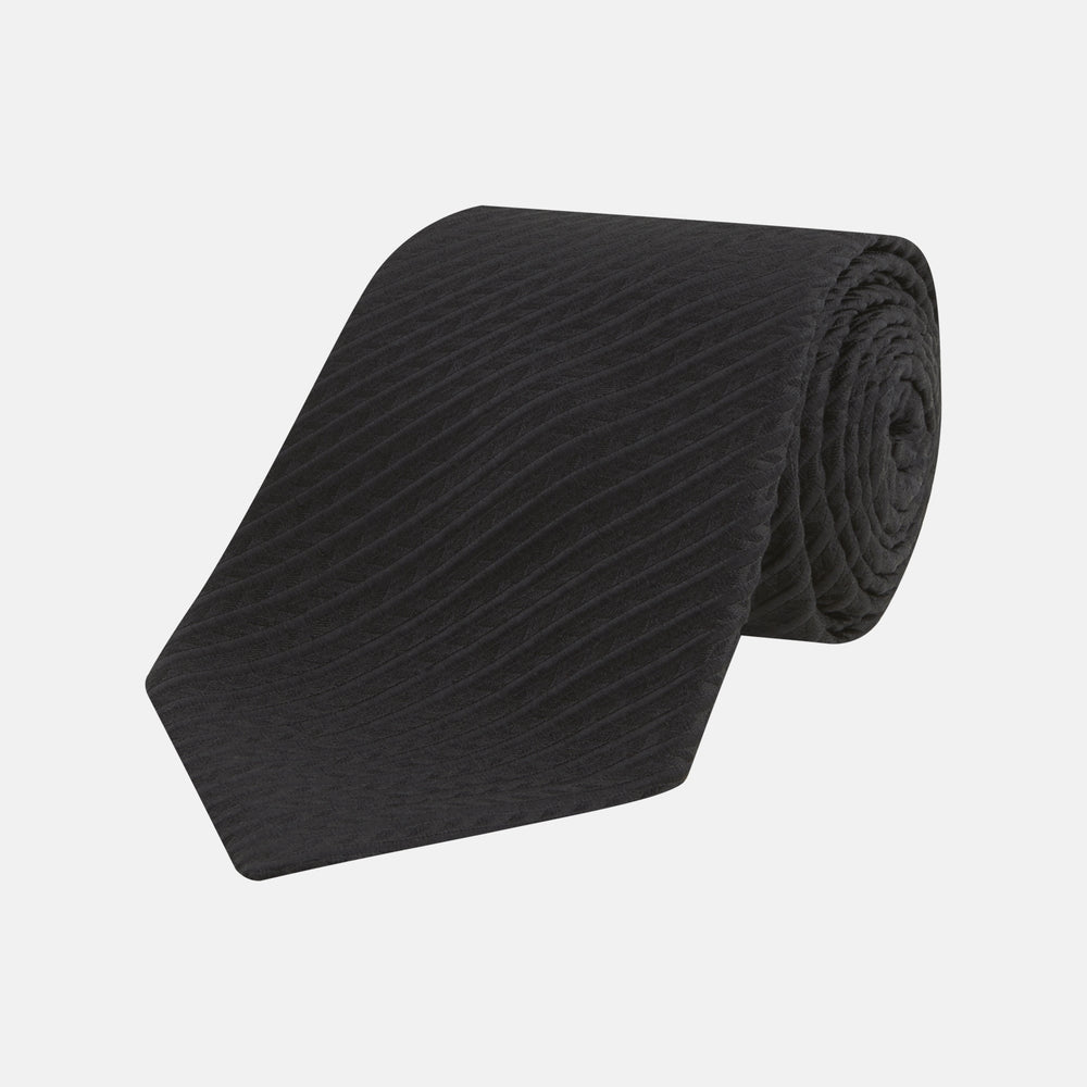 The Black Ottoman Silk Tie by Turnbull & Asser features a subtle wavy textured pattern and is crafted from heavyweight ribbed silk, shown rolled up against a plain white background.