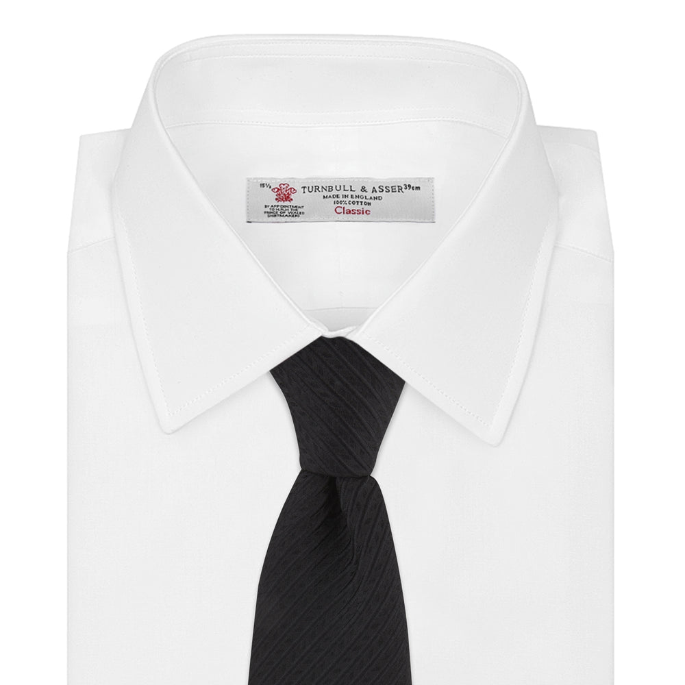 The Black Ottoman Silk Tie by Turnbull & Asser features a subtle wavy textured pattern and is crafted from heavyweight ribbed silk, shown rolled up against a plain white background.