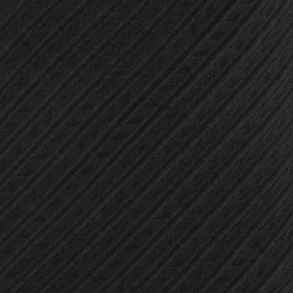 The Black Ottoman Silk Tie by Turnbull & Asser features a subtle wavy textured pattern and is crafted from heavyweight ribbed silk, shown rolled up against a plain white background.
