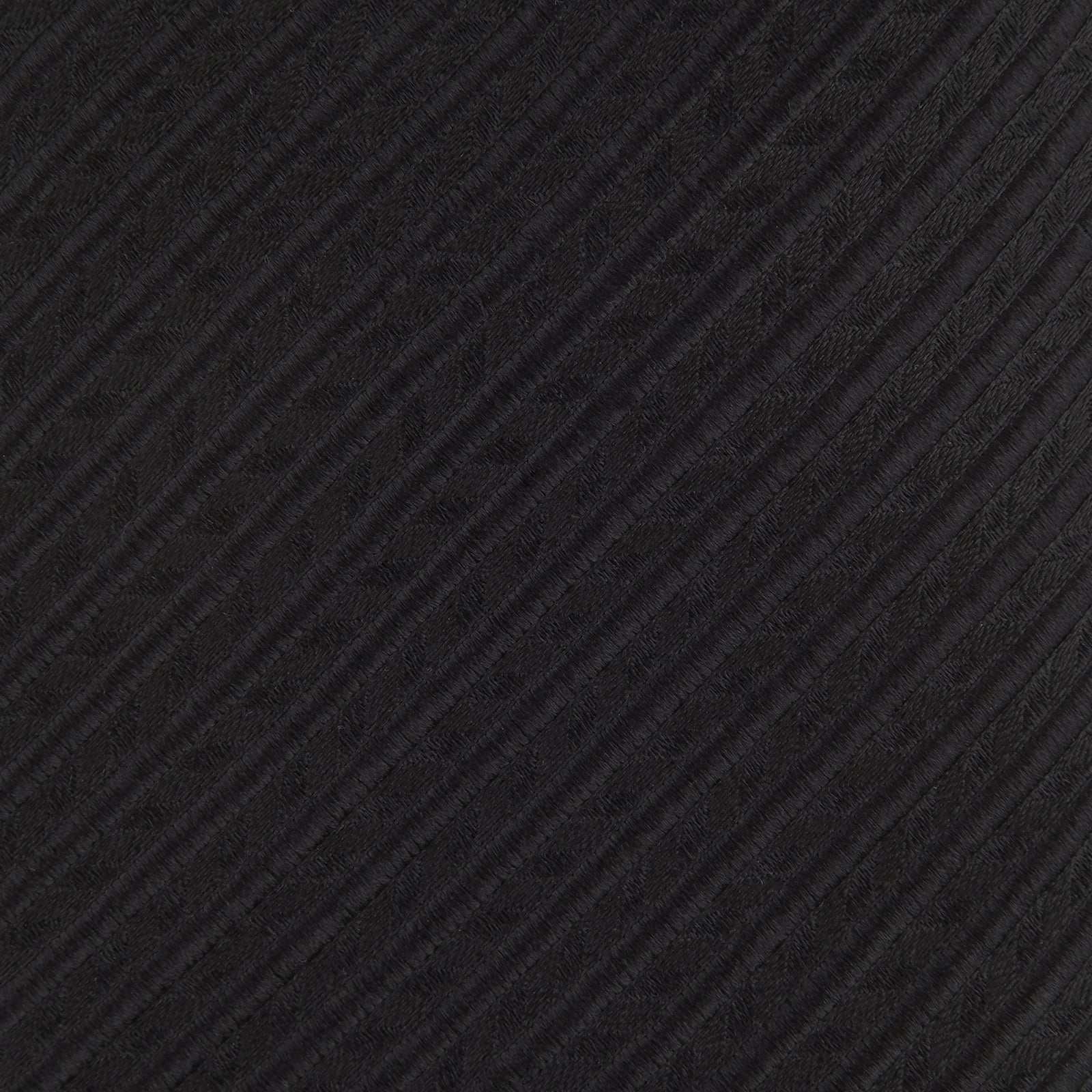 View 3 of product The Black Ottoman Silk Tie by Turnbull & Asser features a subtle wavy textured pattern and is crafted from heavyweight ribbed silk, shown rolled up against a plain white background.