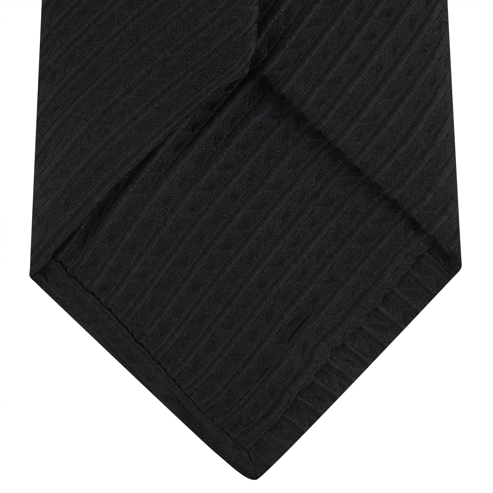 View 4 of product The Black Ottoman Silk Tie by Turnbull & Asser features a subtle wavy textured pattern and is crafted from heavyweight ribbed silk, shown rolled up against a plain white background.