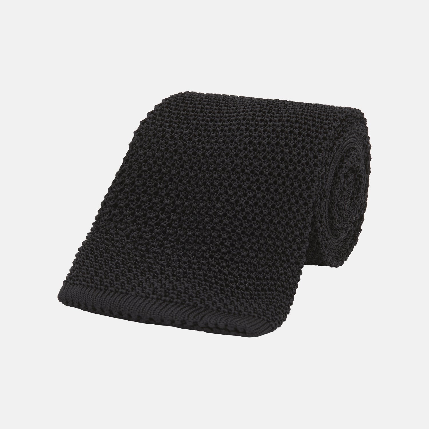 View 1 of product The Turnbull & Asser Black Knitted Silk Tie features a textured pattern and is displayed rolled up on a white background—a stylish, versatile accessory perfect for elevating any gentleman's wardrobe.