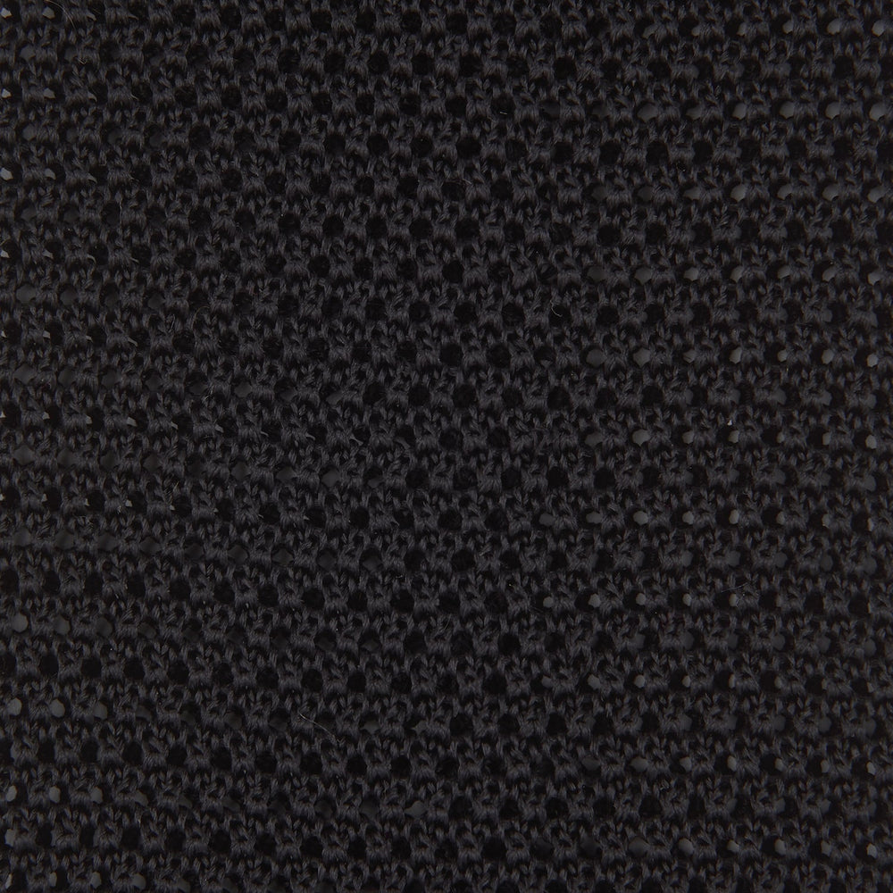 The Turnbull & Asser Black Knitted Silk Tie features a textured pattern and is displayed rolled up on a white background—a stylish, versatile accessory perfect for elevating any gentleman's wardrobe.