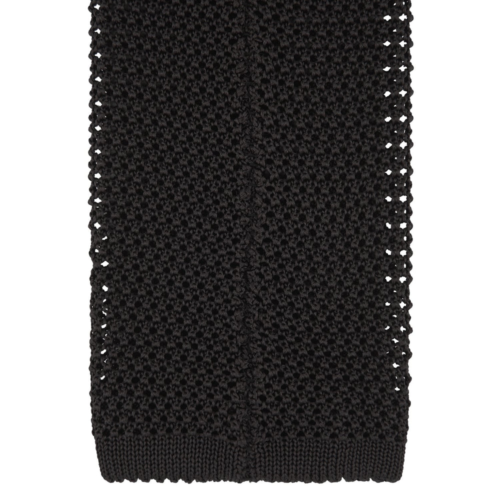 The Turnbull & Asser Black Knitted Silk Tie features a textured pattern and is displayed rolled up on a white background—a stylish, versatile accessory perfect for elevating any gentleman's wardrobe.