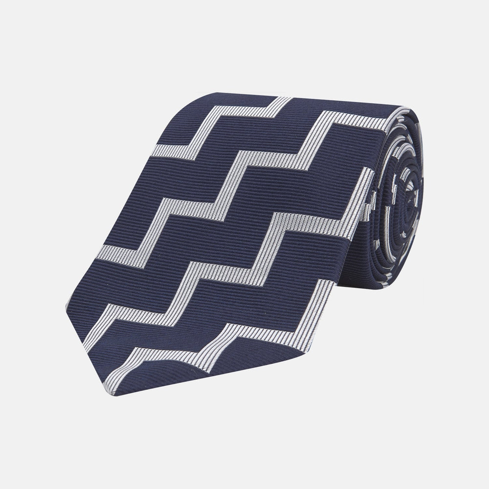The Navy and White Striped Zigzag Silk Tie by Turnbull & Asser, shown rolled on a white background, features bold zigzag stripes—an ideal accessory for the modern gentleman’s everyday style.