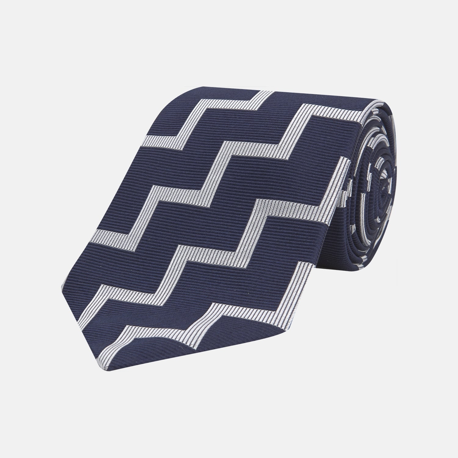 View 1 of product The Navy and White Striped Zigzag Silk Tie by Turnbull & Asser, shown rolled on a white background, features bold zigzag stripes—an ideal accessory for the modern gentleman’s everyday style.