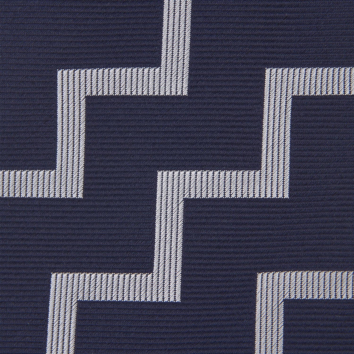 View 3 of product The Navy and White Striped Zigzag Silk Tie by Turnbull & Asser, shown rolled on a white background, features bold zigzag stripes—an ideal accessory for the modern gentleman’s everyday style.