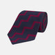 The Turnbull & Asser Navy and Red Striped Zigzag Silk Tie, featuring a striking pattern, is elegantly rolled on a white background—ideal for the modern gentleman.
