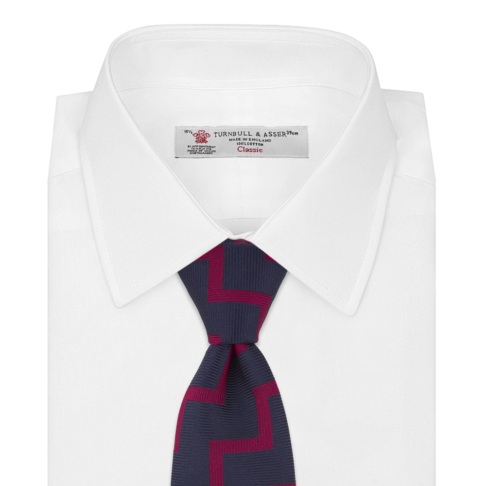 The Turnbull & Asser Navy and Red Striped Zigzag Silk Tie, featuring a striking pattern, is elegantly rolled on a white background—ideal for the modern gentleman.