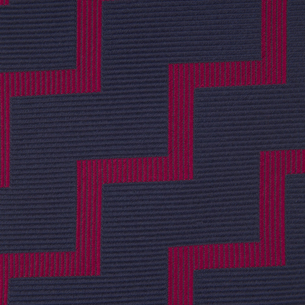 The Turnbull & Asser Navy and Red Striped Zigzag Silk Tie, featuring a striking pattern, is elegantly rolled on a white background—ideal for the modern gentleman.