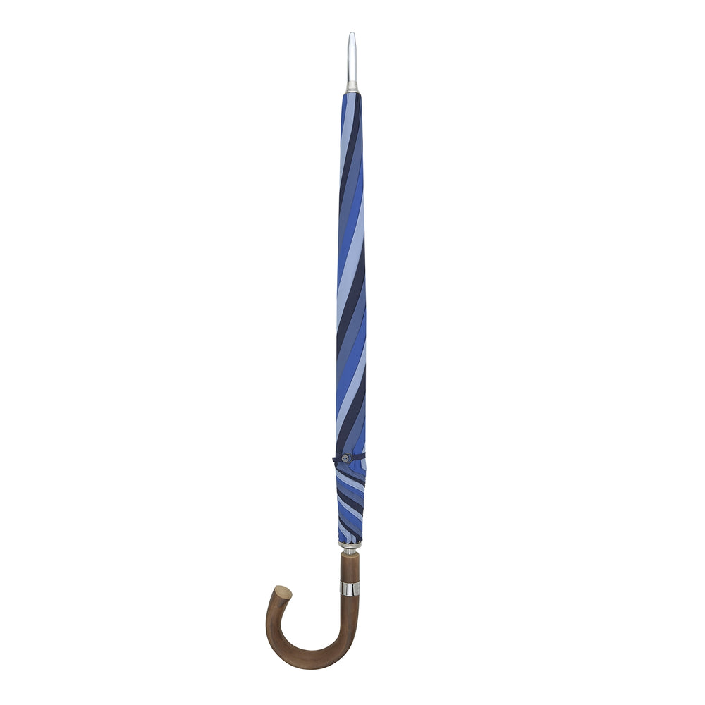 The Turnbull & Asser Sky, Royal Blue and Navy Umbrella with Chestnut Crook features alternating blue panels, a chestnut curved handle, and a silver shaft, making it stand out against a plain white background.