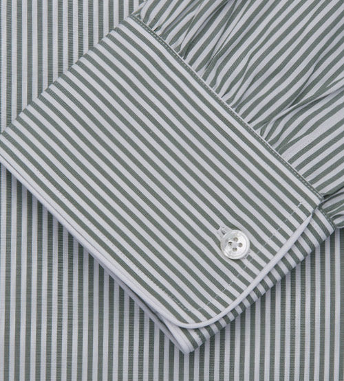 Close-up of a dress shirt with vertical green and white stripes, showing a buttoned cuff with a white button and neatly stitched edging.