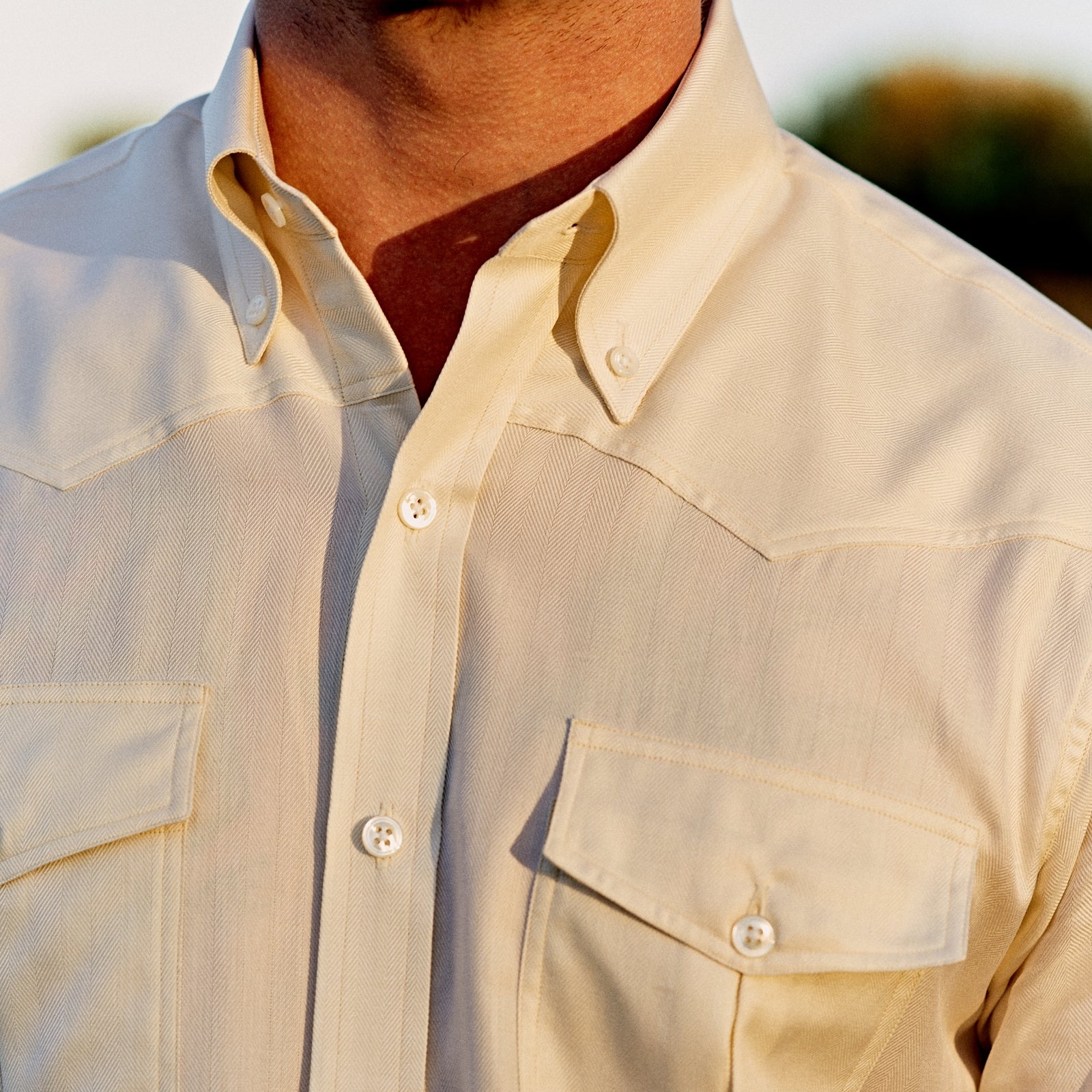 View 3 of product The Turnbull & Asser Weekend Fit Cream Herringbone Western Shirt features a Norfolk collar, button cuffs, and chest pockets, elegantly folded and displayed on a plain white background.