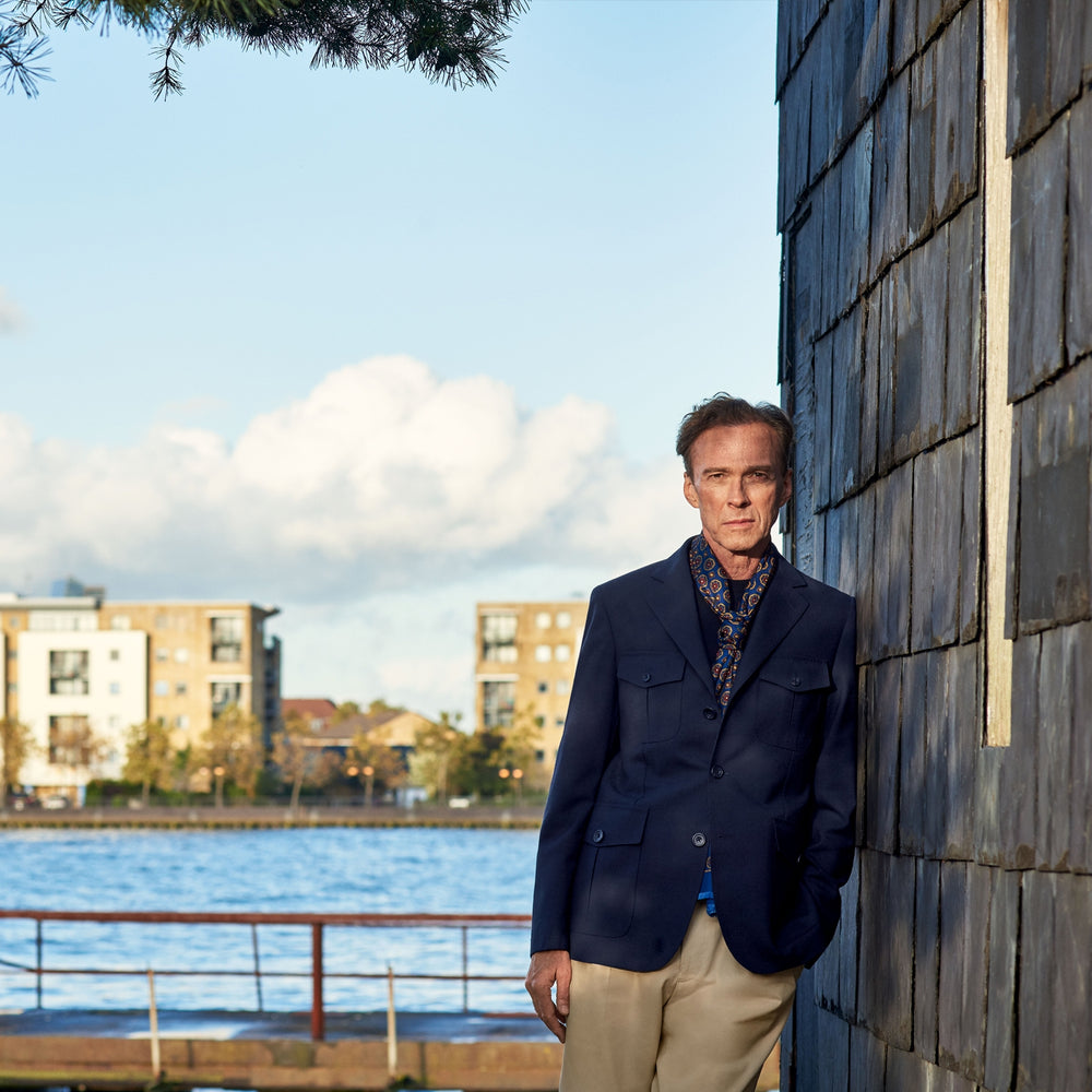 The Turnbull & Asser Navy Lightweight Wool Hopsack Traveller Jacket features a notched lapel, three front buttons, and four flap pockets—two on the chest and two at the waist—all displayed on a plain white background.