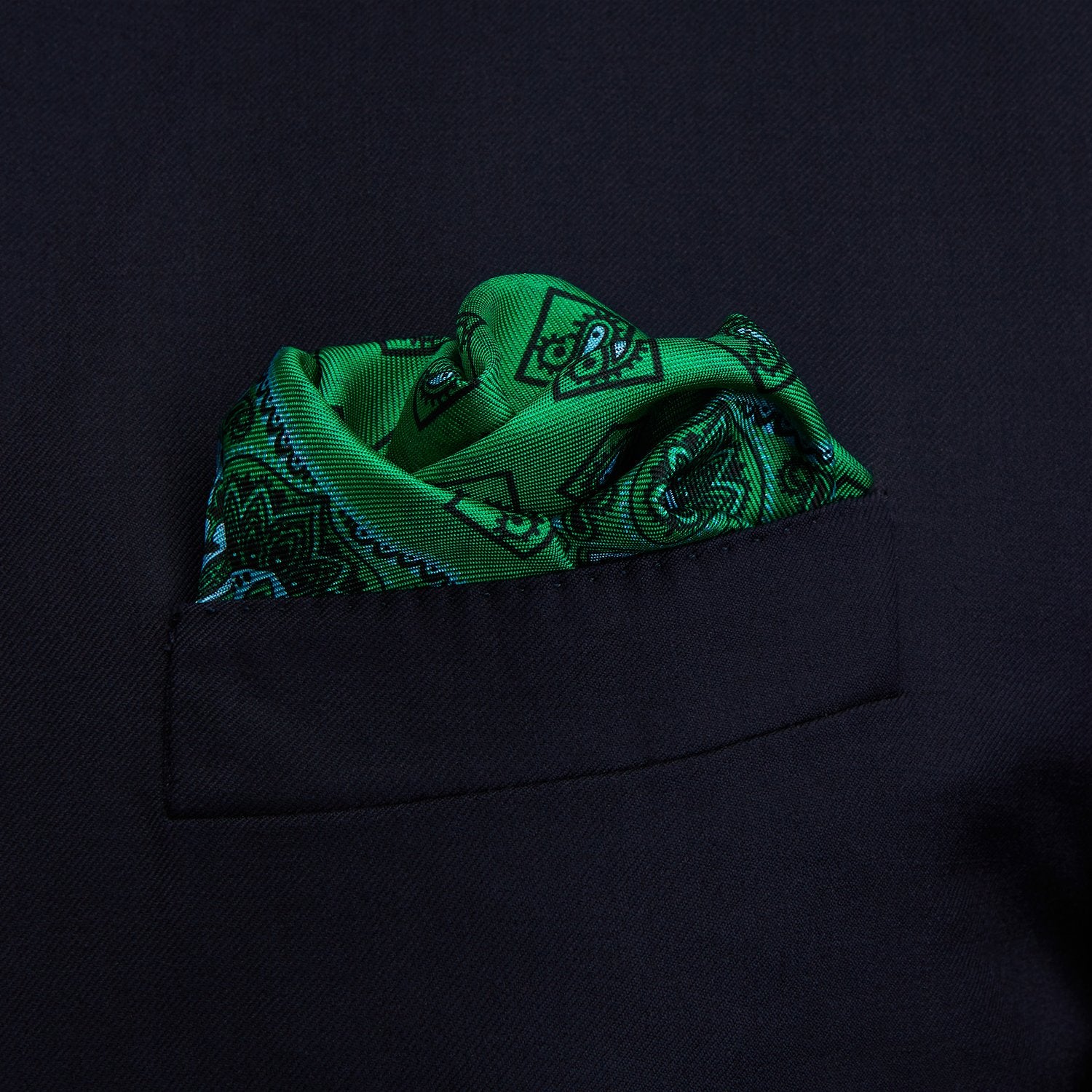 View 2 of product The Green & Blue Double-Faced Paisley Silk Bandana Pocket Square by Turnbull & Asser features a detailed paisley and geometric print with brand accents at the corners.