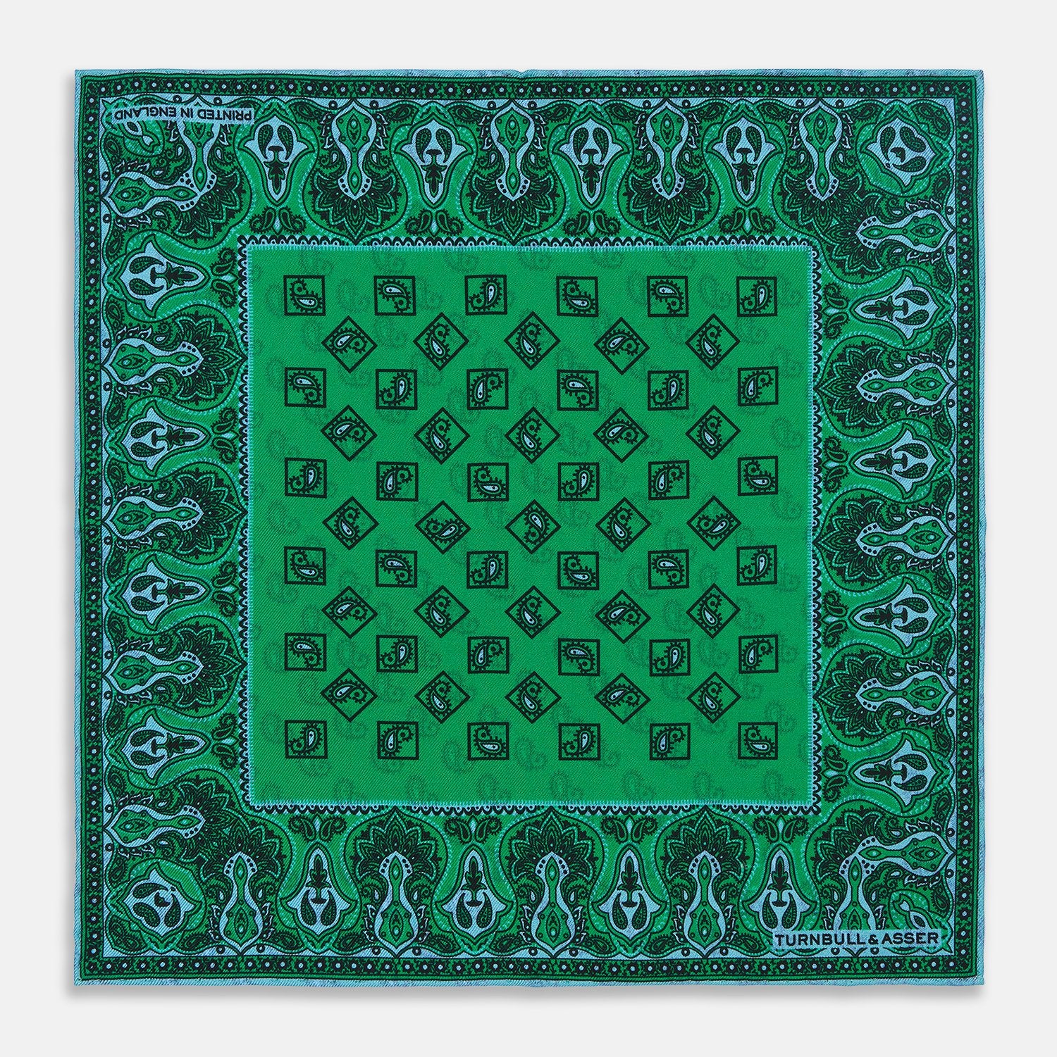 View 1 of product The Green & Blue Double-Faced Paisley Silk Bandana Pocket Square by Turnbull & Asser features a detailed paisley and geometric print with brand accents at the corners.
