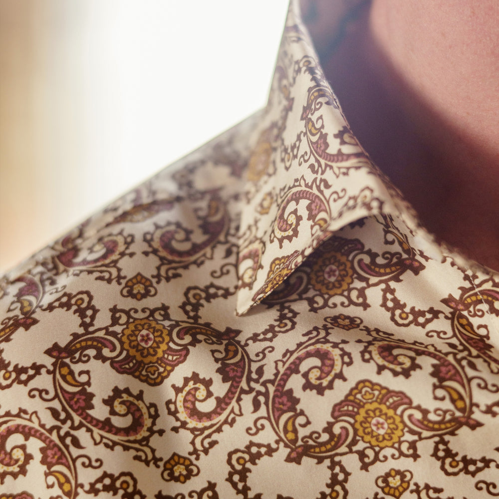 The Turnbull & Asser Tailored Fit Cream Jagger Print Silk Shirt features a Kent collar, 2-button cuffs, and an intricate brown and gold print on cream silk for timeless elegance.