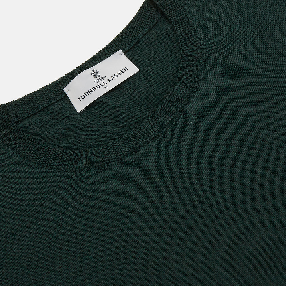 The Turnbull & Asser Forest Green Crew Neck Merino Jumper features ribbed cuffs and hem for a classic look. Laid flat on a white background, this luxury long-sleeve sweater is an essential, timeless addition to any wardrobe.