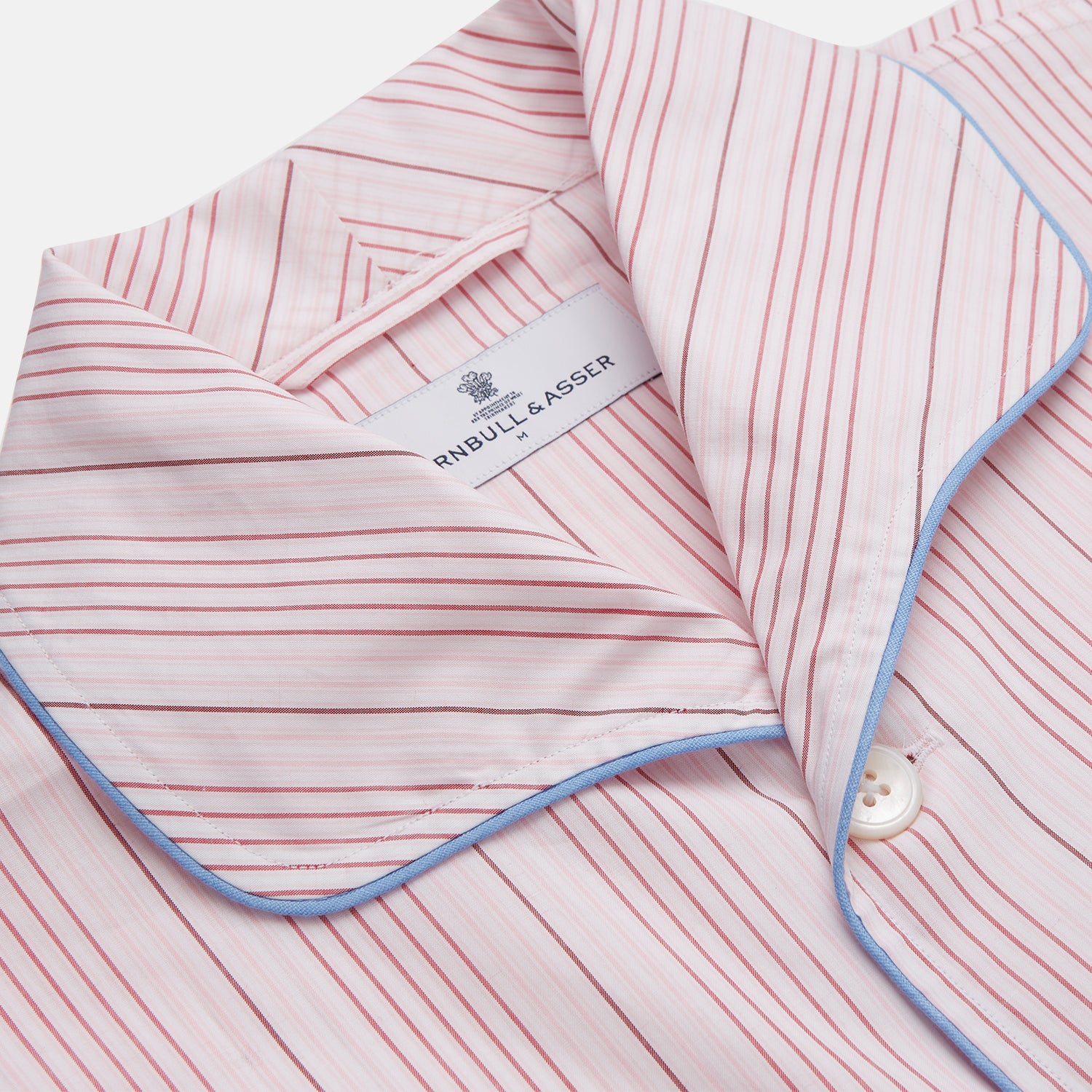 View 2 of product The Turnbull & Asser Pink And White Stripe Twill Cotton Pyjama Set features long sleeves and pants with a curved collar and blue trim on the cuffs, pocket, and hem—a classic gent’s style shown on a plain white background.