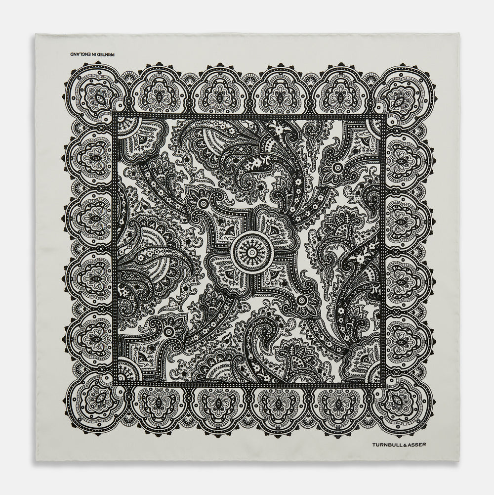 The White Persian Paisley Pocket Square by Turnbull & Asser features a refined black paisley and floral pattern with a decorative border, making it a sophisticated, festive gift.