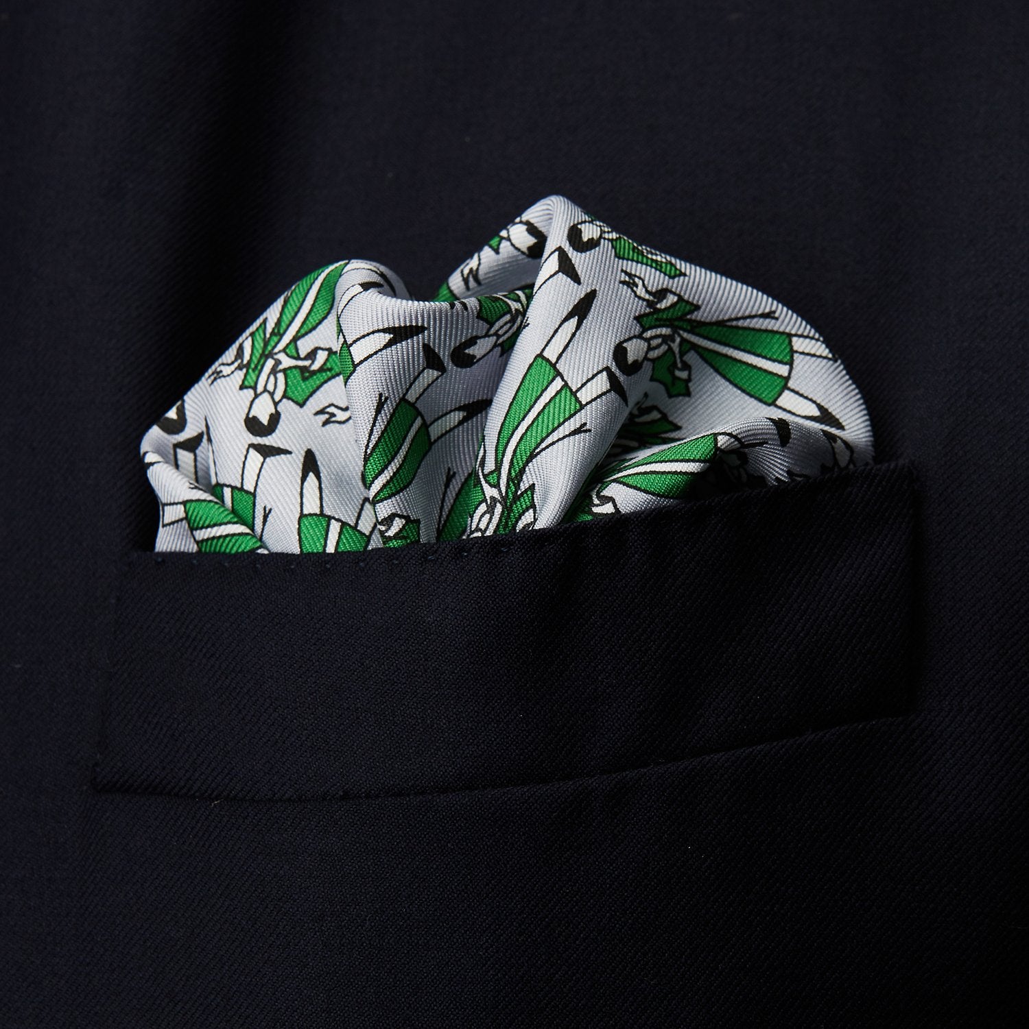 View 2 of product The Turnbull & Asser Green Dressing Gowns Pocket Square features a white silk base with green lines and a repeating pattern of green and black illustrated golfers, inspired by classic Turnbull dressing gown designs.