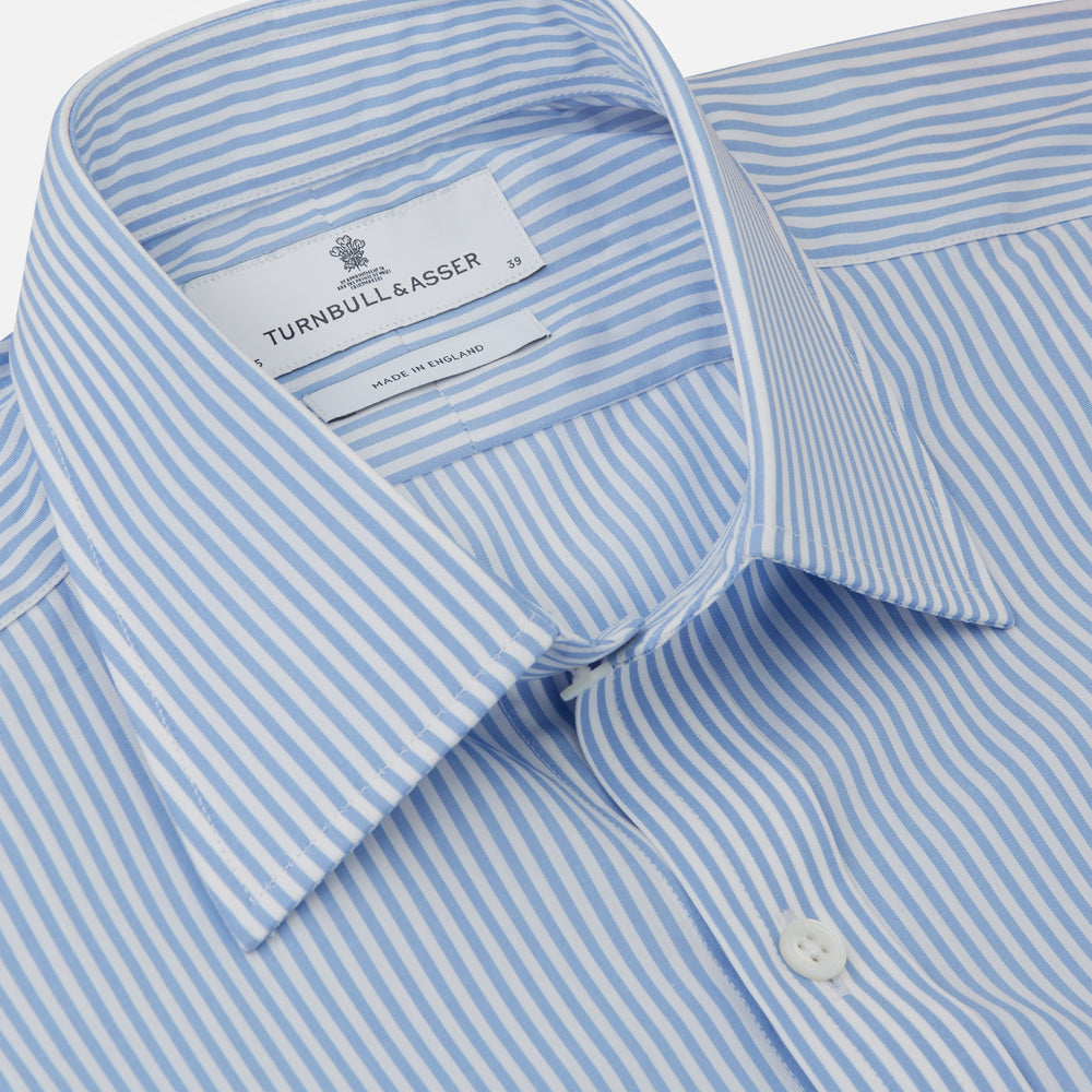 The Turnbull & Asser Light Blue Bengal Stripe Shirt features white vertical stripes, a classic T&A collar, and 3-button cuffs. Buttoned down the front, it’s laid flat on a white background for a timeless British look.