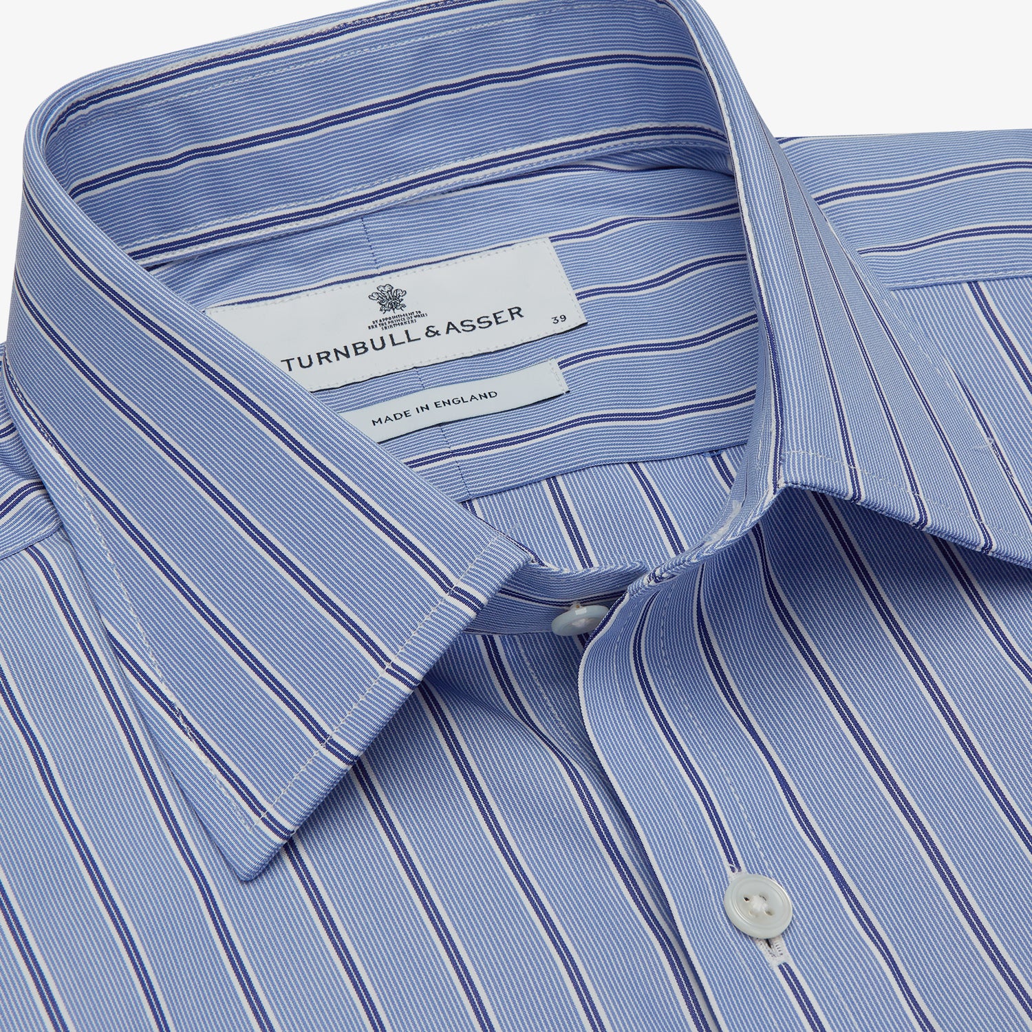 View 4 of product A neatly folded Turnbull & Asser Blue Stripe Regular Fit Shirt with T&A collar and square double cuffs, featuring long sleeves and thin white stripes on a light blue base, displayed on a plain white background.