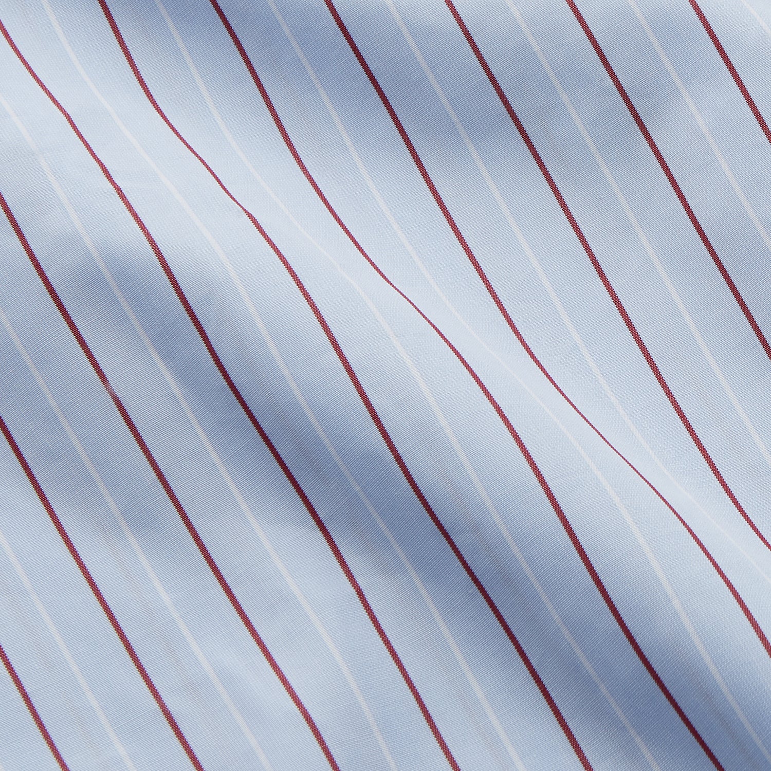 View 4 of product The Turnbull & Asser Burgundy Stripe Regular Fit Shirt features a T&A collar, double cuffs, and white buttons. Made from light blue Italian cotton poplin with vertical burgundy and white pinstripes. Laid flat on a white background.