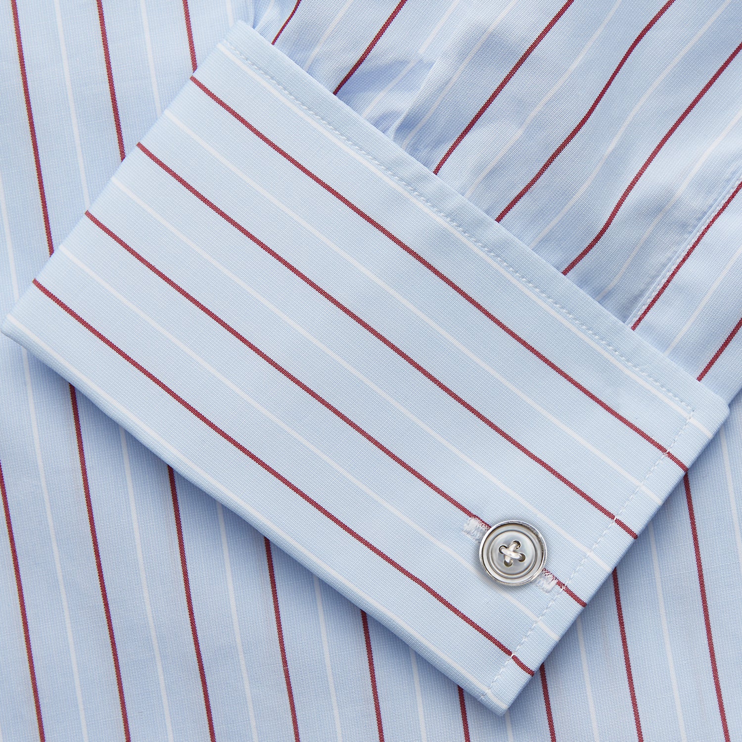 View 3 of product The Turnbull & Asser Burgundy Stripe Regular Fit Shirt features a T&A collar, double cuffs, and white buttons. Made from light blue Italian cotton poplin with vertical burgundy and white pinstripes. Laid flat on a white background.