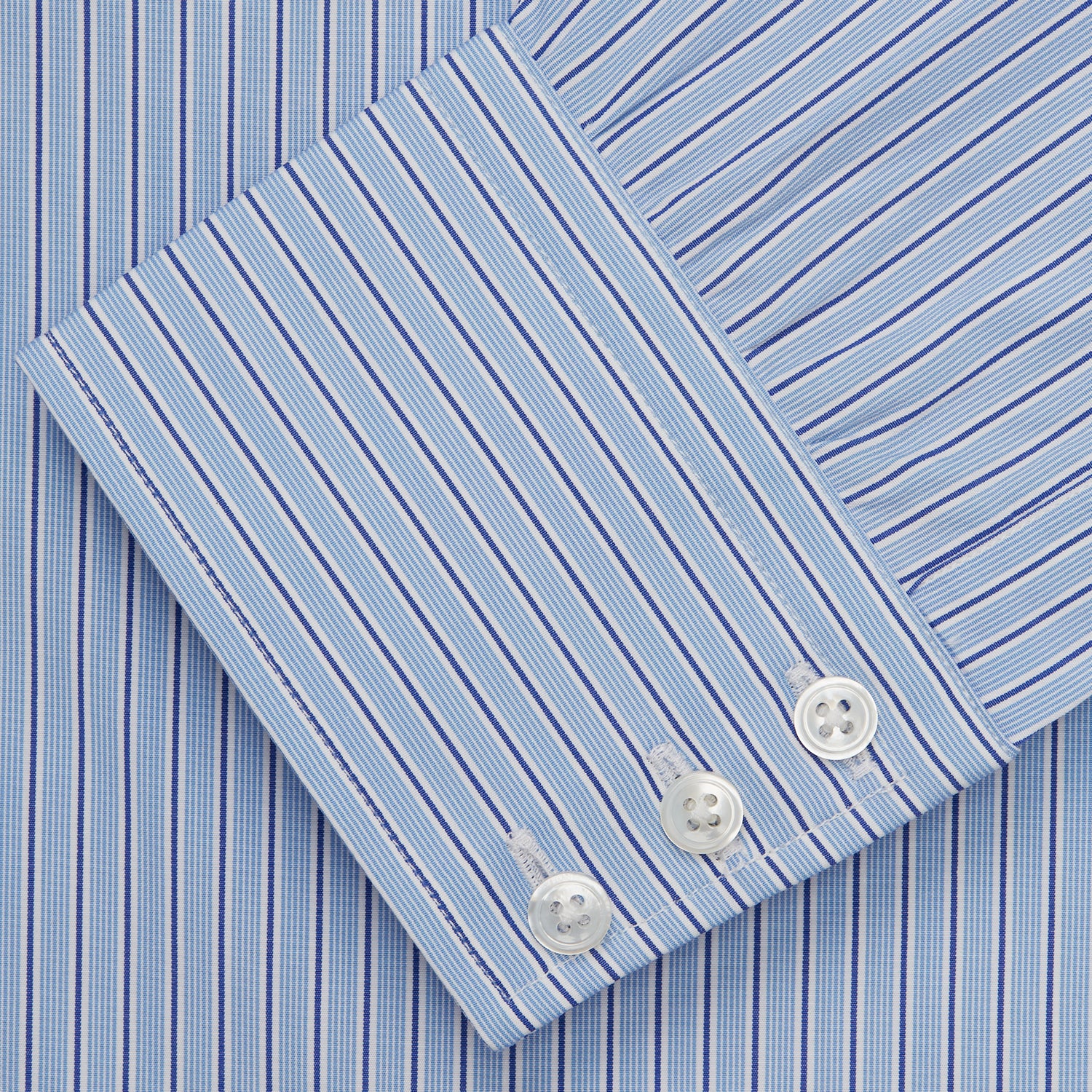 View 5 of product Turnbull & Asser’s Blue Stripe Shirt features thin vertical white stripes, a T&A collar, 3-button cuffs, white buttons, and a regular fit. Smart-casual style displayed flat on a white background.