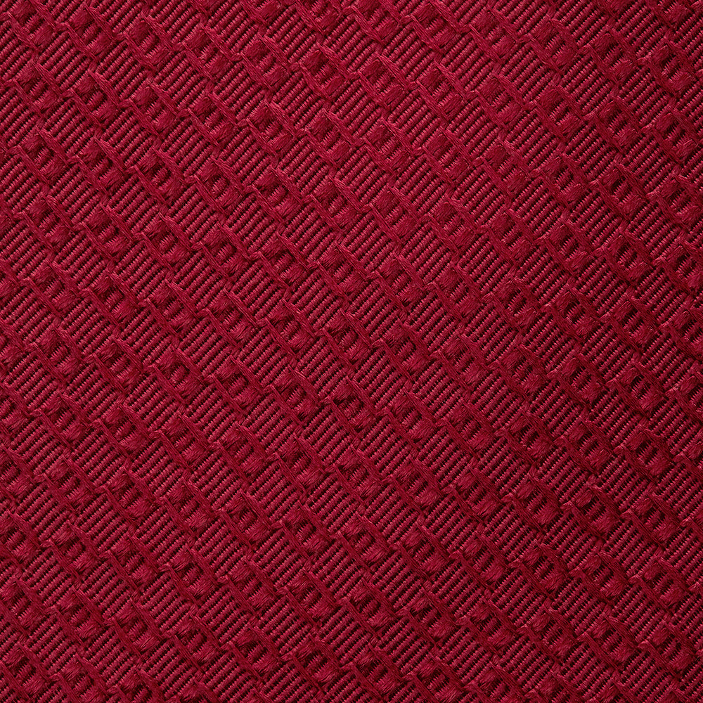 The Turnbull & Asser Burgundy Abstract Tonal Silk Jacquard Tie is shown rolled up with a subtle textured pattern on a plain white background—an elegant formalwear choice.
