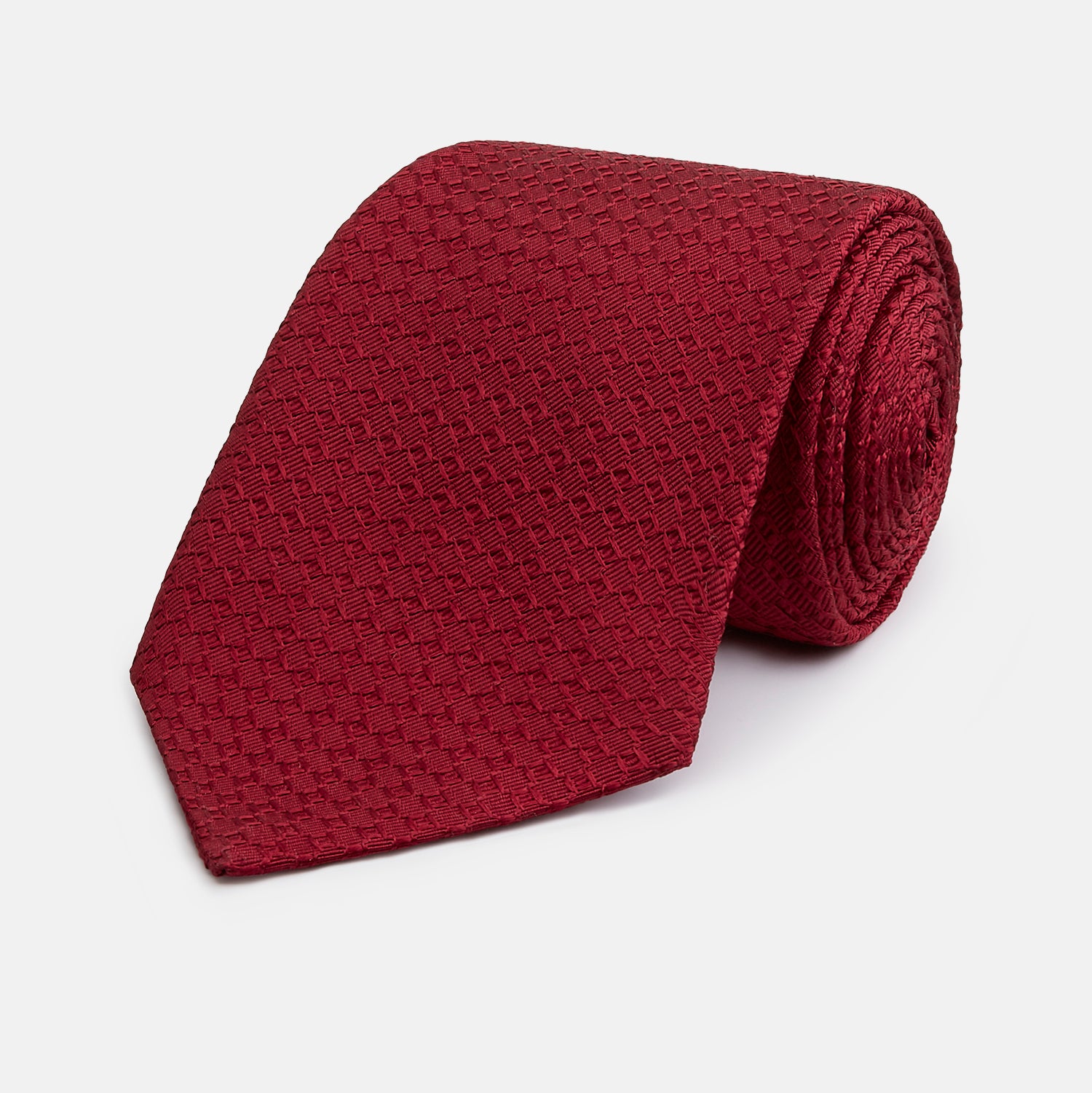 View 1 of product The Turnbull & Asser Burgundy Abstract Tonal Silk Jacquard Tie is shown rolled up with a subtle textured pattern on a plain white background—an elegant formalwear choice.